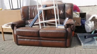 Eski püskü deri ve ahşap mobilyalar sokakta duruyor. Çöp yığınları, mobilyalar, eşyalar, ev eşyaları çöp kamyonuyla kaldırılmadan önce sokakta duruyordu..