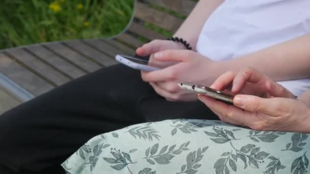 어머니와 아들은 공원에서 벤치에 스마트 폰을보고 화면을 누르고 자신의 전화를 — 비디오
