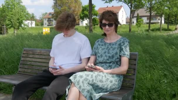 Adult Mother Teenager Son Sit Bench Summer Park Look Smartphone — Stock Video