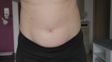 Kadın göbeği pozitif. Kadın ağır çekimde zıplıyor. Spor sutyen ve tayt giyen bir kadının karnında küçük bir yağ tabakası. Spor anlayışı, sağlıklı yaşam tarzı veya kilolu.