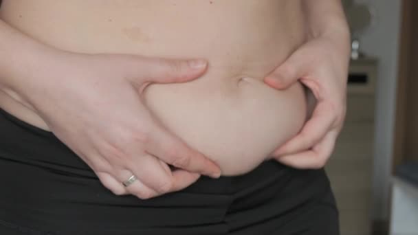 女性腹部身体呈阳性 女人抚平肚子的褶皱 身穿运动胸罩和腿的妇女腹部的一层脂肪 健康生活方式或超重的概念 — 图库视频影像