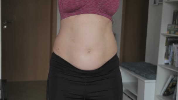 女性の腹の体は陽性です フラットスローモーションでベリーダンスを踊る女性 スポーツブラとレギンスを着用している女性の腹部に脂肪の小さな層 スポーツ 健康的なライフスタイル または太りすぎのコンセプト — ストック動画