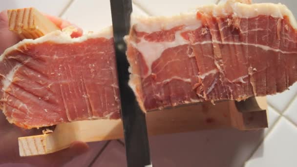 スペインの伝統的な豚ジャム ナイフは キッチンの薄いスライスにハムン肉の一部をカット トップビュー — ストック動画