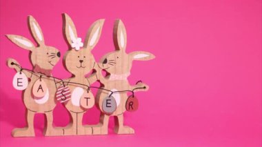 Paskalya Hareketi animasyonu. Güzel Paskalya tavşanları çerçevede hareket ediyorlar. Pembe arka planda Paskalya tabelasını tutuyorlar..