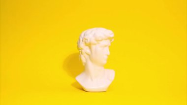 Sarı arka planda hareket eden bir adamın antik heykelinin hareketini durdurun..