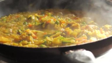 Büyük bir tava köpüklü risotto kaynıyor. Ev mutfağında sebzeli ve tavuklu risotto hazır..