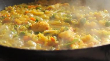 Büyük bir tava köpüklü risotto kaynıyor. Ev mutfağında sebzeli ve tavuklu risotto hazır..
