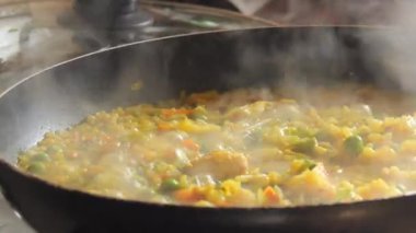 Büyük bir tava köpüklü risotto kaynıyor. Ev mutfağında sebzeli ve tavuklu risotto hazır..