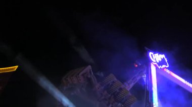 6 Nisan 2024 - Kehl, Almanya: Aydınlatılmış dönen sarkacın gece yolculuğu. Aile ve arkadaşlar için eğlence parkı. Eğlence alanında dönen çekimin parçaları yavaş çekim.