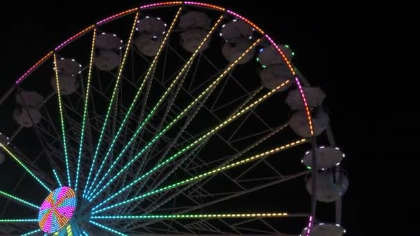 摩天轮在晚上 五颜六色的发光轮转和滚动度假者在其白色的摊位 — 图库视频影像