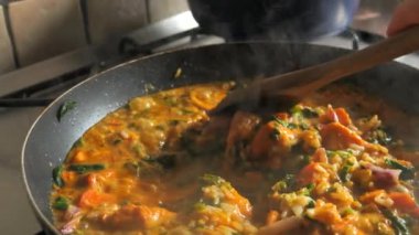 Tavada pilavlı Hint tavuğu ezmesi. Egzotik yemeklerin ev yemeği. Tikka Masala. Baharatlı Hint yemeği. Tereyağlı Basmati Rice. Curry 'yi yavaş çekimde kızartıyorum. Tahta kaşık..