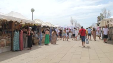 2 Temmuz 2024 - Palma de Mallorca, Mallorca: Palm Katedrali 'nin karşısındaki hediyelik eşya pazarı. Turistler çeşitli el işleri ve mallarla çadırların önünden geçiyorlar