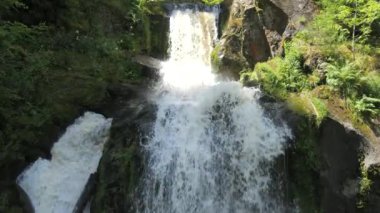 Triberg, Almanya 'daki Kara Orman' ın en yüksek şelalesi. Dağ suyunun yavaş düşüşü. Dağlık bir yerde yeşil yosunlarla kaplı büyük kayalık taşlar..