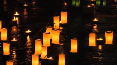 Turuncu kağıt Japon fenerleri gecenin karanlığında suyun üzerinde..