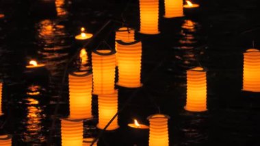 Turuncu kağıt Japon fenerleri gecenin karanlığında suyun üzerinde..