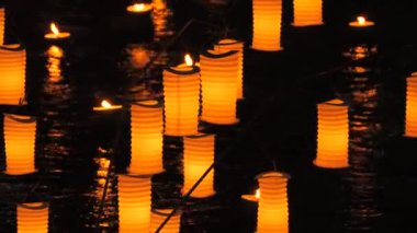 Turuncu kağıt Japon fenerleri gecenin karanlığında suyun üzerinde..