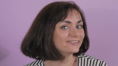 Kablosuz kulaklıkla müzik dinleyen, dans eden ve şarkı söyleyen neşeli genç bir kadının portresi. Mor arka planda bir kadının duyguları, ağır çekim..