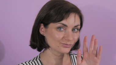 Güzel, genç bir kadının portresi. Gülümsüyor ve yavaşça kameraya doğru elini sıkıyor..