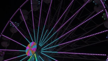 Geceleri dönme dolap. Çok renkli Aydınlatılmış tekerlek, tatilcileri beyaz kabinlerinde döndürür ve yuvarlar..