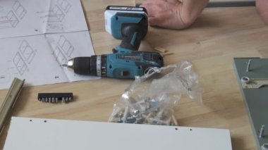 17 Haziran 2024 - Kehl, Almanya: Bir adam evde tek başına mobilya montajı yapıyor. Matkap, çekiç, diyagram ve talimatlar yakında..