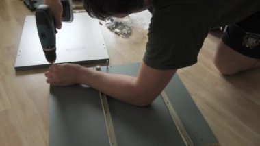 17 Haziran 2024 - Kehl, Almanya: Bir adam evde tek başına mobilya montajı yapıyor. Matkap, çekiç, diyagram ve talimatlar yakında..