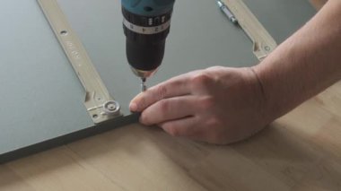 Matkabın yakın çekim görüntüsü. Adamın biri evdeki tahtaya vidayla vuruyor..