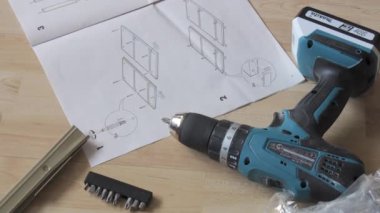 17 Haziran 2024 - Kehl, Almanya: Bir adam evde tek başına mobilya montajı yapıyor. Matkap, çekiç, diyagram ve talimatlar yakında..