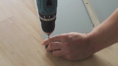 Matkabın yakın çekim görüntüsü. Adamın biri evdeki tahtaya vidayla vuruyor..