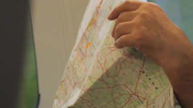 Erkek el, alanın fiziksel haritasını tutuyor. Ağır çekimde seyredilen yüksek hızlı bir trende seyahat ediyor..