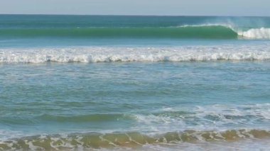 Okyanus dalgalarının yuvarlanıp sahile çarpıp büyüleyici ve sakinleştirici doğal bir manzara yarattıkları güzel, yavaş çekim görüntüleri. Turkuaz sular ve beyaz köpük çarpıcı bir şekilde yakalanıyor.
