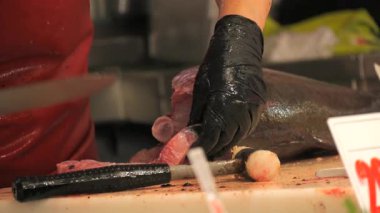 Yetenekli bir balıkçı, taze bir ton balığını yavaş çekimde dilimliyor. Deniz ürünleri hazırlamadaki hassasiyet ve tekniğini gösteriyor. Ayrıntılı yakın çekim zengin dokuyu vurgular