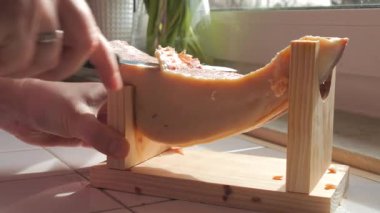 Güzel, yaşlı bir İspanyol jamonu, ahşap bir standın üzerinde uzanır, zengin dokusu ve sıcak güneş ışığıyla vurgulanmış, hassas bir el, ince dilimlenmiş bir parçaya uzanır ve bu geleneksel kurutulmuş lezzetin özünü yakalar.