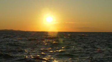 Sakin Adriyatik Denizi 'nin üzerinde, ılık ışığı yansıtan hafif dalgalarla batan güzel altın güneş. Hırvatistan 'ın Zadar kentinde yakalanan bu sakin deniz manzarası barışı, seyahat hayallerini ve ebedi güzelliği çağrıştırıyor