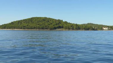 Hırvatistan 'ın Adriyatik kıyısında yoğun çam ormanı ve berrak mavi suyu olan yemyeşil bir adanın huzurlu manzarası. Seyahat, doğa ya da rahatlama temaları için ideal