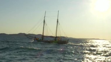 Eski moda bir yelkenli Adriyatik güneşinin altın parıltısıyla dalgaların arasından geçiyor. Deniz parıldıyor ve ufuk özgürlük vaat ediyor.