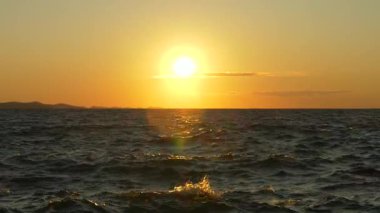 Sakin Adriyatik Denizi 'nin üzerinde, ılık ışığı yansıtan hafif dalgalarla batan güzel altın güneş. Hırvatistan 'ın Zadar kentinde yakalanan bu sakin deniz manzarası barışı, seyahat hayallerini ve ebedi güzelliği çağrıştırıyor
