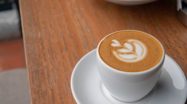 Macchiato kahvesi, seçici odak noktasında, kahve dükkanındaki ahşap masanın üzerinde.