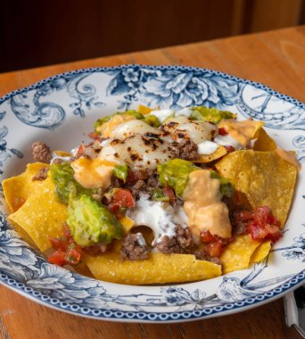 Kızarmış kıymalı mısır cipsi ve ahşap zemin üzerinde guacamole..