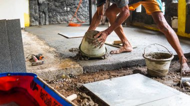 Erkek bir inşaat işçisi büyük seramik bir fayans yerleştirir.