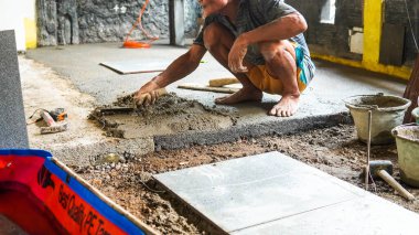 Jakarta, Endonezya 23 Haziran 2023: Erkek bir inşaat işçisi büyük bir seramik fayans döşedi