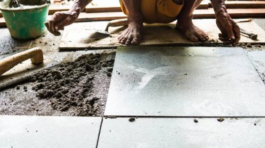 Erkek bir inşaat işçisi büyük seramik bir fayans yerleştirir.