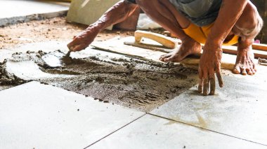 Erkek bir inşaat işçisi büyük seramik bir fayans yerleştirir.