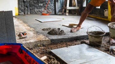 Erkek bir inşaat işçisi büyük seramik bir fayans yerleştirir.