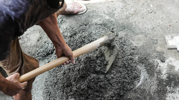 stock image Asian worker using hoe for mixing cement power with sand