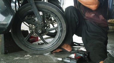 Motosikletin lastiğini değiştiren, kenarı tutan, yakın plan. Otomotiv onarım kılavuzları, motosiklet bakım rehberleri ve mekanik web siteleri için elverişli.