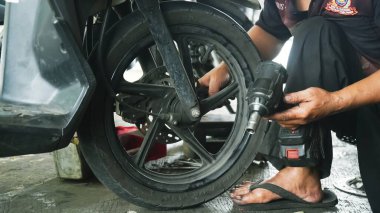 Motosikletin lastiğini değiştiren, kenarı tutan, yakın plan. Otomotiv onarım kılavuzları, motosiklet bakım rehberleri ve mekanik web siteleri için elverişli.