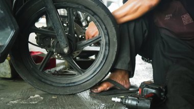 Motosikletin lastiğini değiştiren, kenarı tutan, yakın plan. Otomotiv onarım kılavuzları, motosiklet bakım rehberleri ve mekanik web siteleri için elverişli.
