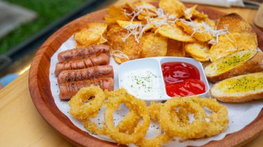 Kızarmış patates ve kızarmış soğan halkalarının fotoğrafı, restoranda bir fotoğrafta, kırmızı biber sosuyla servis ediliyor.