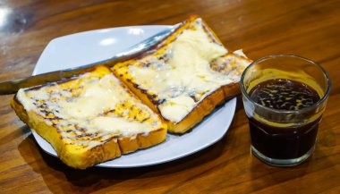 Lezzetli kızarmış sandviç, ızgara, erimiş tereyağı ve seçici odak noktasında bir fincan kahve..