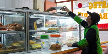 Cakarta, Endonezya 23 Haziran 2024 Warteg lokantasında yemek yiyen online bir motosiklet sürücüsü